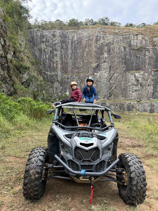 Participantes em um UTV diante de um paredão natural.